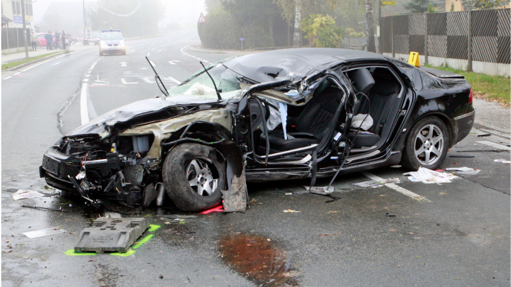 Black sedan crumpled after a car crash highlighting the speed it takes to die in a car crash