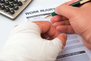 filling up a work injury claim form with a wrapped hand 300x201 1