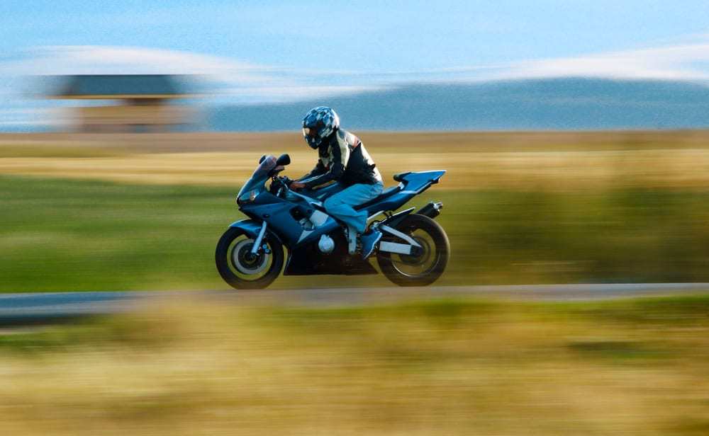 Motorcyclist driving fast on country road blurred background